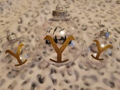 three glass ornaments with gold designs on them