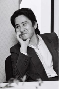 a black and white photo of a woman sitting at a table with her hand on her face