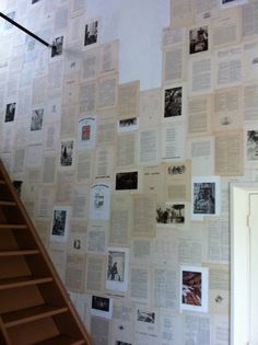 the wall is covered with many old newspaper pages, and there are stairs leading up to it