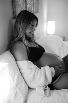 a pregnant woman wrapped in a blanket sitting on a bed