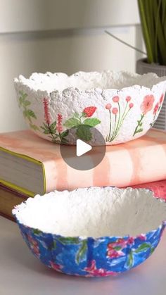 three bowls sitting on top of each other next to a book and vase with flowers