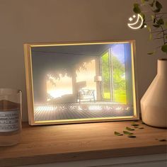 an illuminated photo frame sitting on top of a table next to a vase with flowers