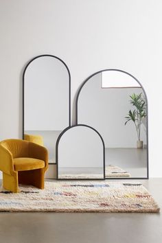 two chairs sitting on top of a rug in front of a mirror and potted plant