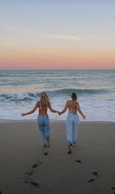 two women walking on the beach holding hands