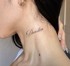 a woman with a small tattoo on her neck saying, deceitn in cursive writing