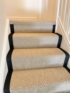 a set of stairs with carpeted treads and black trim on the bottom handrail