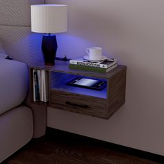 a table with a book, coffee cup and tablet on it next to a bed