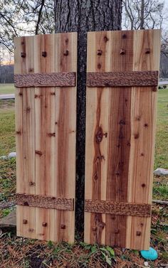 two wooden doors that are next to a tree