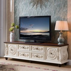 a large flat screen tv sitting on top of a white dresser