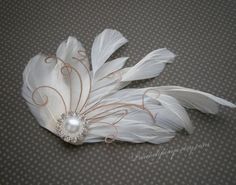 a white feather and pearl brooch on a gray background