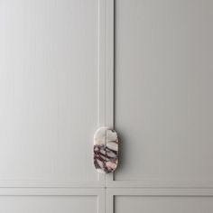 a marble door handle on the side of a white painted cabinet with grey paneling