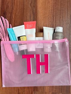 a pink mesh bag filled with personal care items on top of a wooden floor next to a door