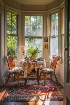 a table and chairs in front of two windows with potted plants on top of them