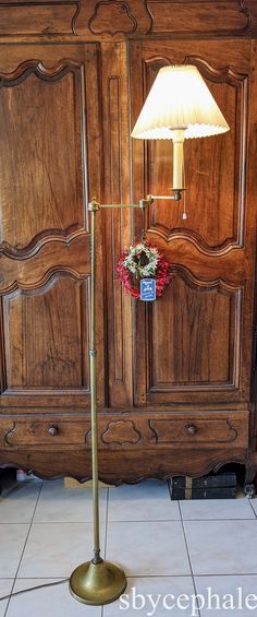 a lamp is sitting on the floor next to a wooden armoire