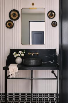 a black and white bathroom with gold accents on the wall, mirror above the sink