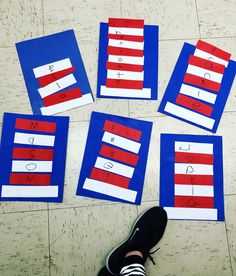 four red, white and blue paper strips laid out on the floor to spell letters