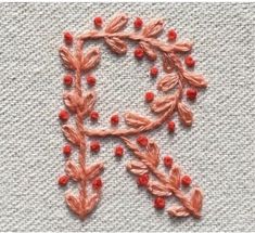 an embroidered letter is shown with red beads