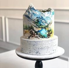 a three tiered cake decorated with mountains and lakes