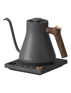 an electric tea kettle on top of a box with a wooden spoon in the handle