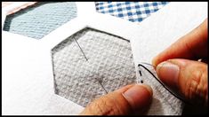 someone is cutting out some fabric on top of a piece of paper with scissors and thread