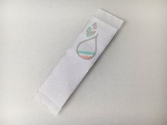 a white bookmark with a green and pink design on the front, sitting on top of a table