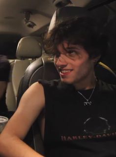 a young man sitting in the back seat of a car