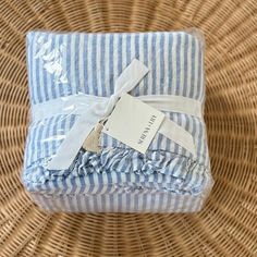 a blue and white striped blanket sitting on top of a wicker basket next to a tag