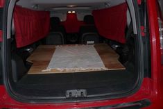 the back end of a red van with an area rug in the cargo compartment that has been folded over