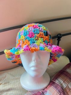 a white mannequin head wearing a multicolored crocheted sun hat