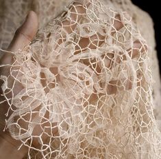 a hand holding a piece of lace in it's palm