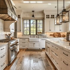 a large kitchen with white cabinets and wood flooring, along with an island in the middle