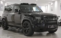 a black land rover is parked in a showroom