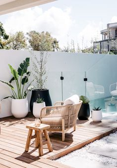 a wooden deck with wicker furniture and potted plants