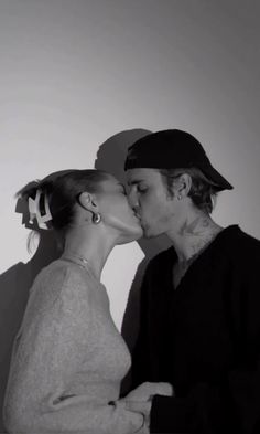 a man and woman kissing each other in black and white