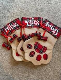 three christmas stockings with red and black plaid designs on them, tied to the floor