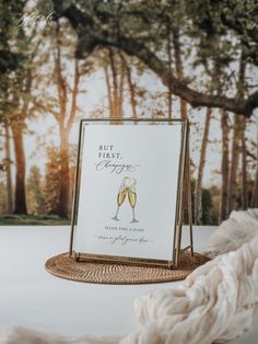 a sign that is on top of a wicker mat with some wine glasses in it