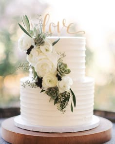 a wedding cake with white flowers and greenery on top