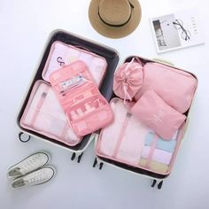 three pieces of pink luggage sitting on top of a white table next to a straw hat