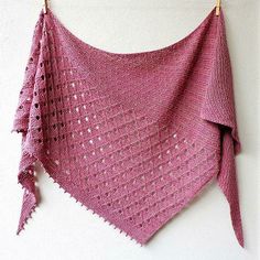 a crocheted shawl hanging from a hook on a wall with white background