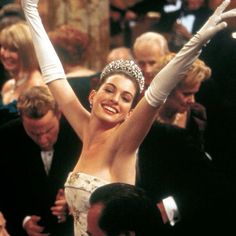 a woman wearing a tiara and holding her arms in the air