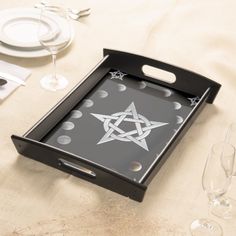 a black tray with a pentagramil design on the side and wine glasses next to it