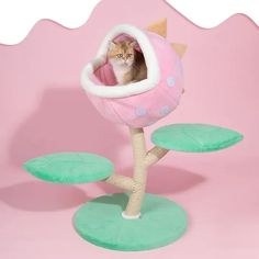 a cat sitting in a pink and white ball shaped tree house on top of green bases