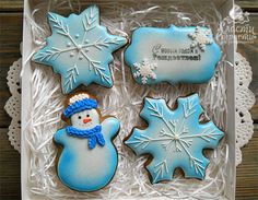 three decorated cookies in a box with snowflakes on the top and two frosted ones