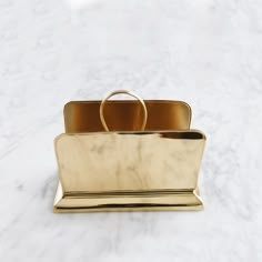 a gold ring sits on top of a white marble countertop, holding a golden purse