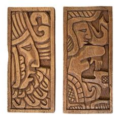 two carved wooden plaques with faces and designs on the sides, one is made out of wood