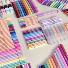 many different colored pens and pencils are laid out next to each other on a table