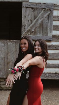 two beautiful young women standing next to each other in front of a wooden barn door