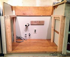 an unfinished kitchen cabinet with the door open and some tools in place on the floor