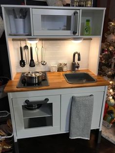 a small kitchen with a sink, stove and christmas tree in the backround