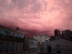 the sky is pink and cloudy over some buildings